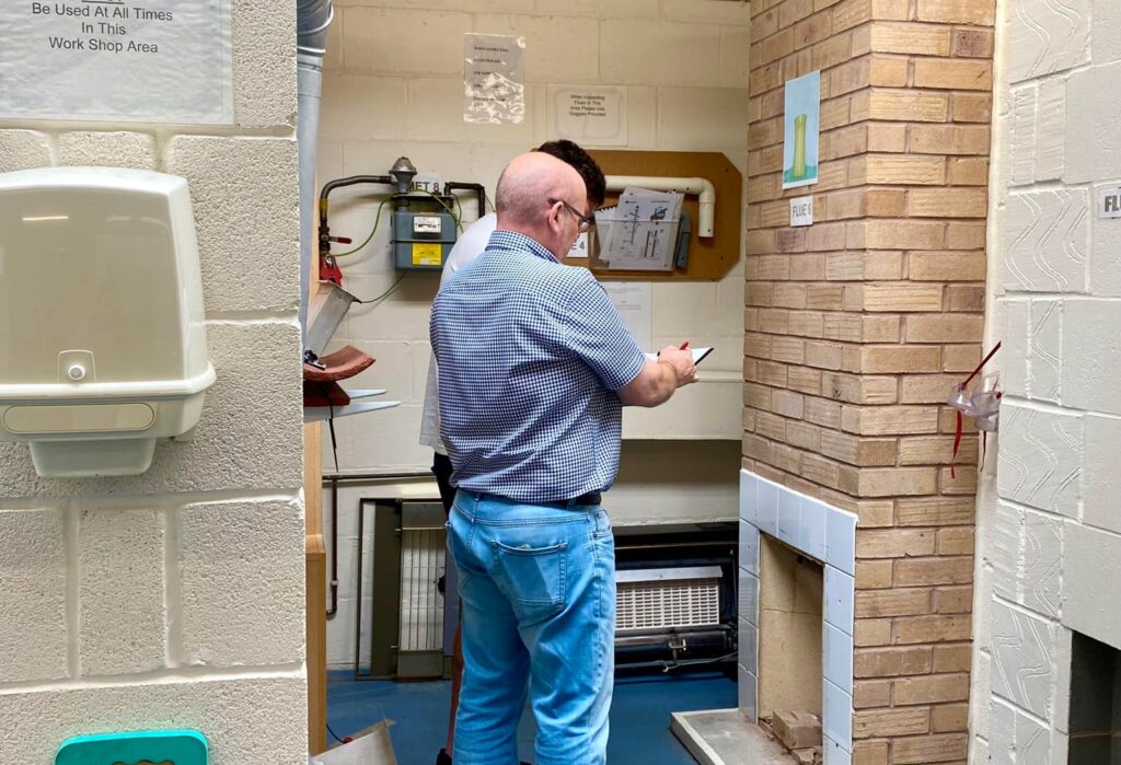 Two men looking at paperwork in a bay which has a fireplace in it doing a domestic natural gas ACS Training and Assessments